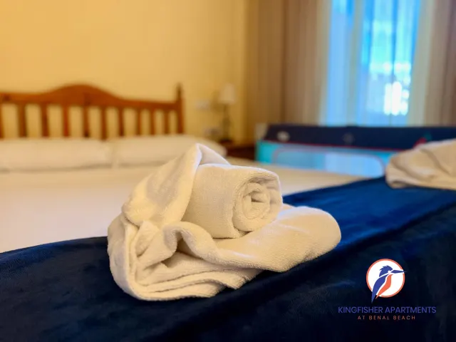 Family apartment — Fresh towels in the main bedroom, with a travel cot in the background