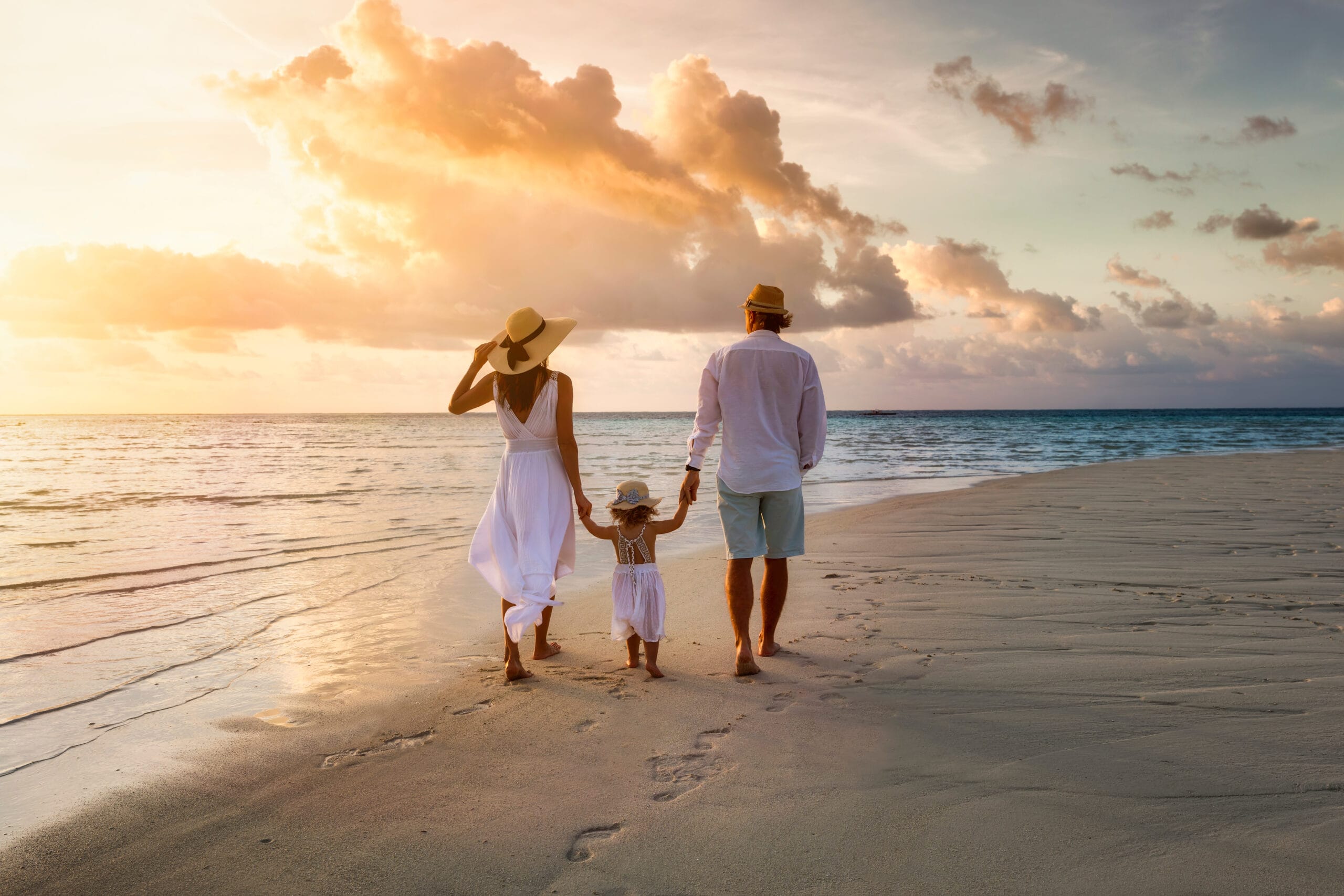 Family walking together along a beach at sunset