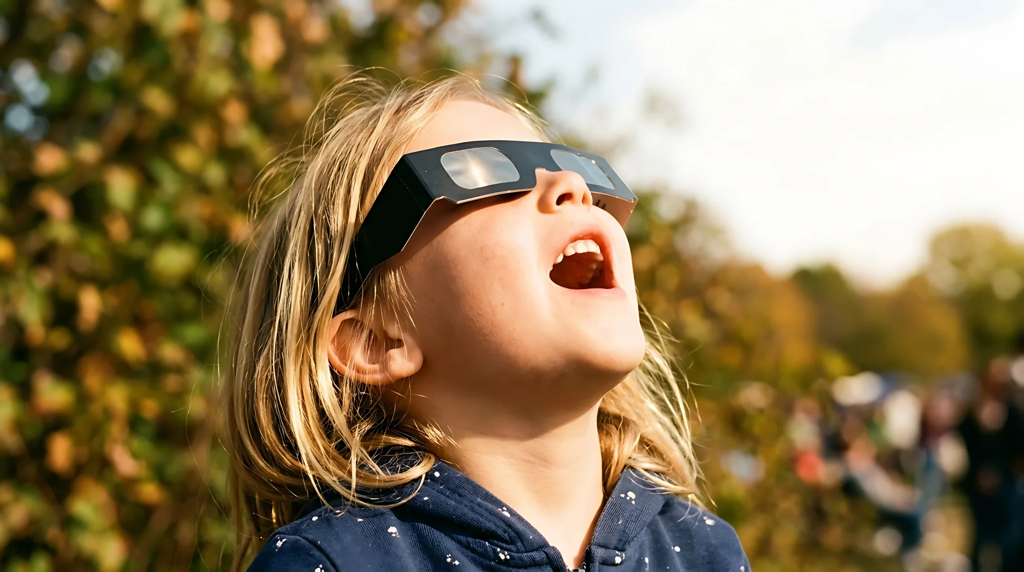 Child looking up through protective solar eclipse glasses