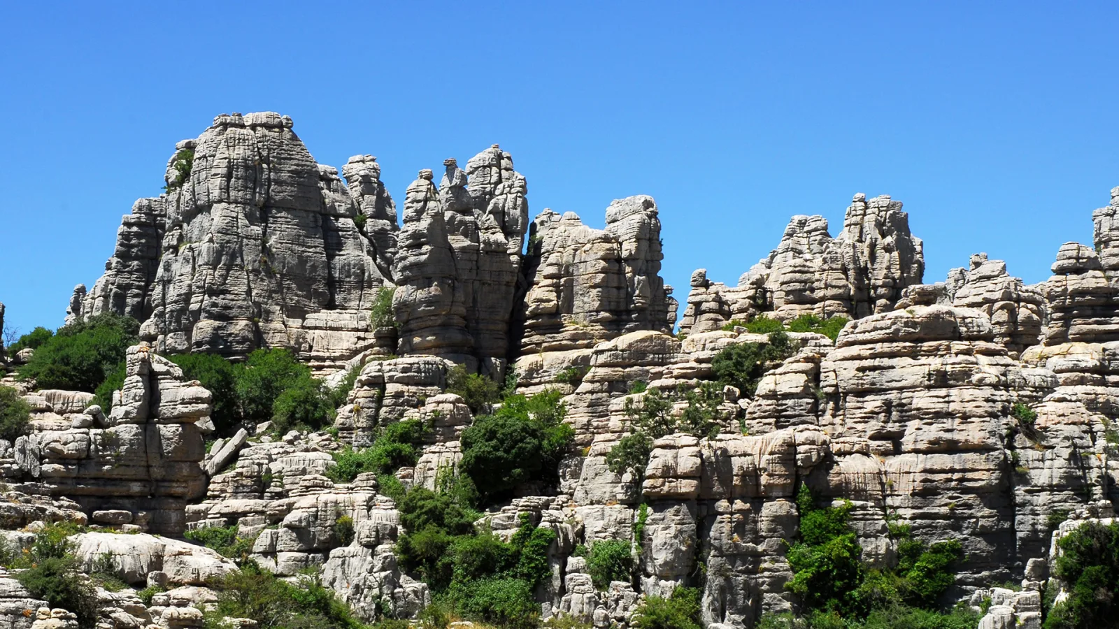 Gelaagde kalkstenen rotsformaties onder een blauwe lucht bij El Torcal de Antequera