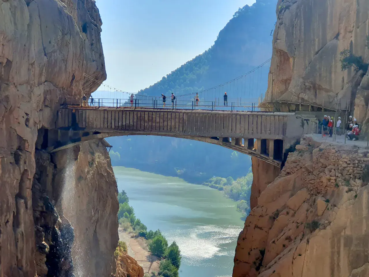 Hikers crossing the cliffside suspension bridge above the Gaitanes Gorge on Caminito del Rey