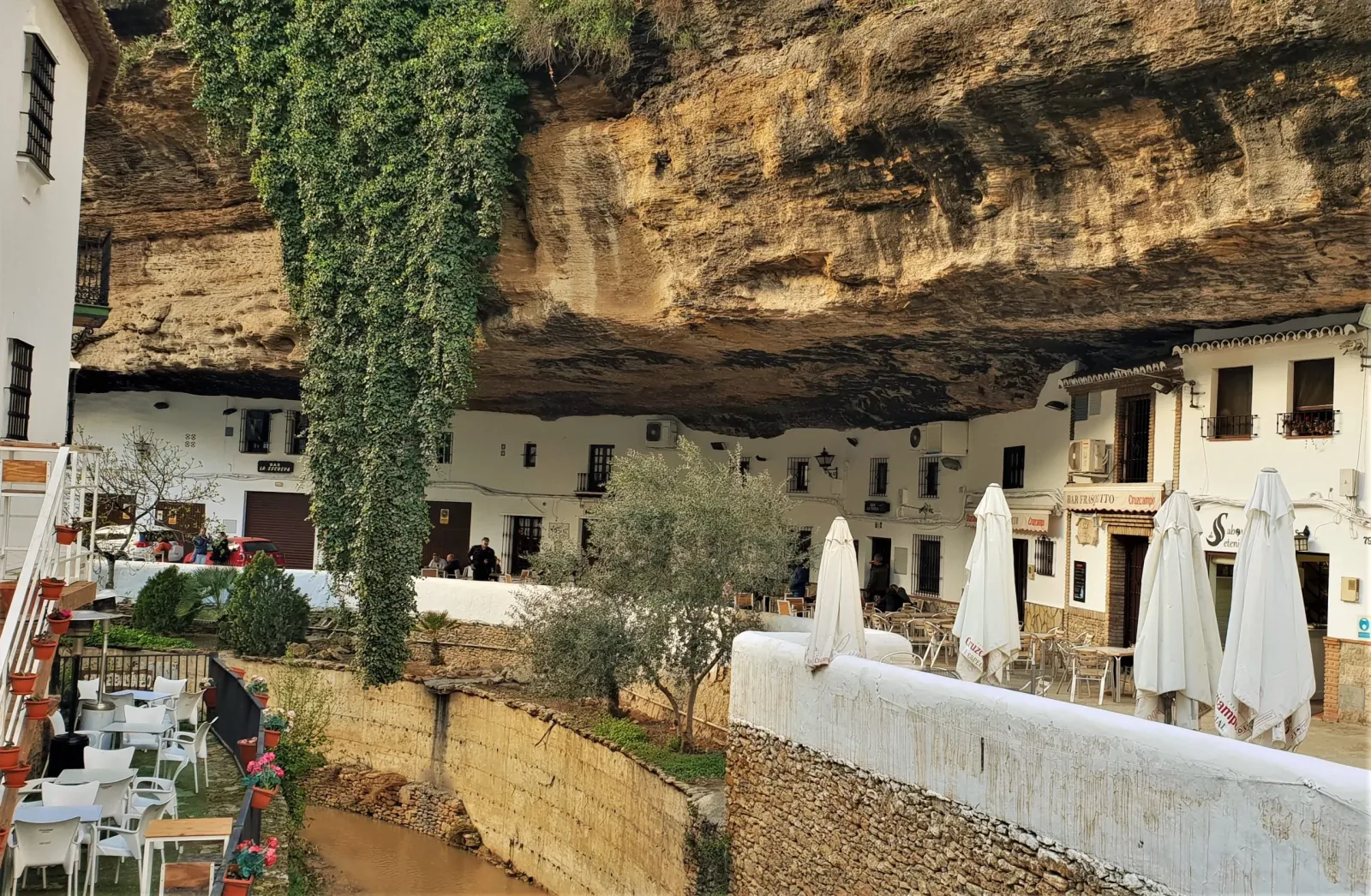 Witgekalkte huizen en cafés gebouwd onder de overhangende rotsen in Setenil de las Bodegas